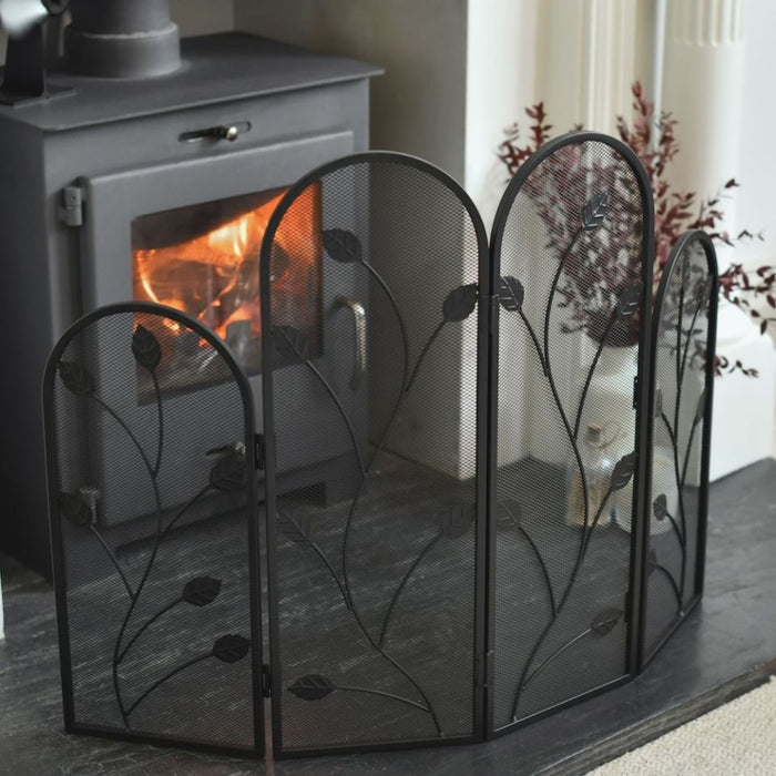 Wood-burning stove with decorative black metal fireplace screen in a home setting.