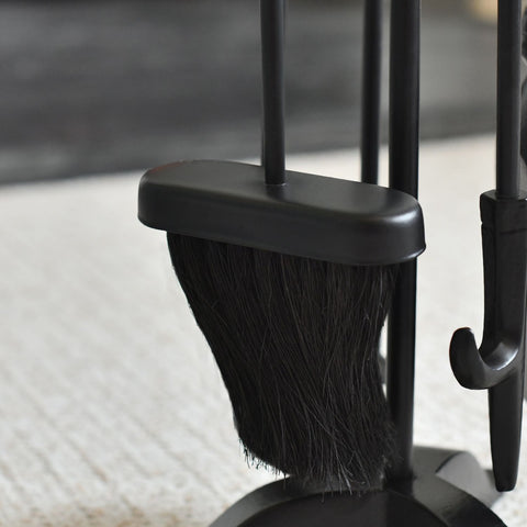 Black broom and dustpan set on a light-colored floor.