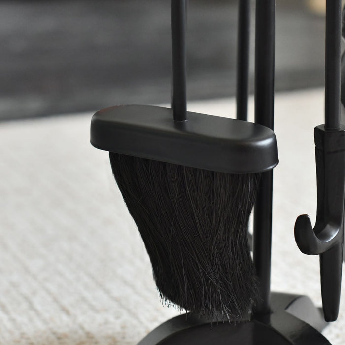 Black broom and dustpan set on a light-colored floor.