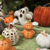 Halloween-themed ceramic pumpkins and ghosts on a wooden surface.