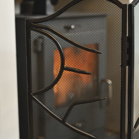 Black metal fireplace screen with mesh design in front of a fire.
