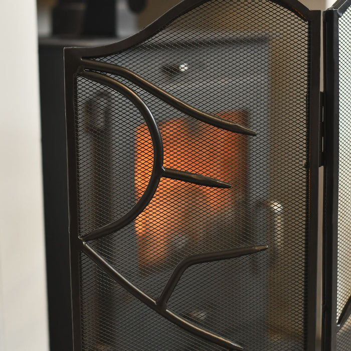 Black metal fireplace screen with mesh design in front of a fire.