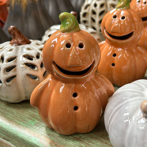 Ceramic pumpkins with smiling faces on a wooden surface