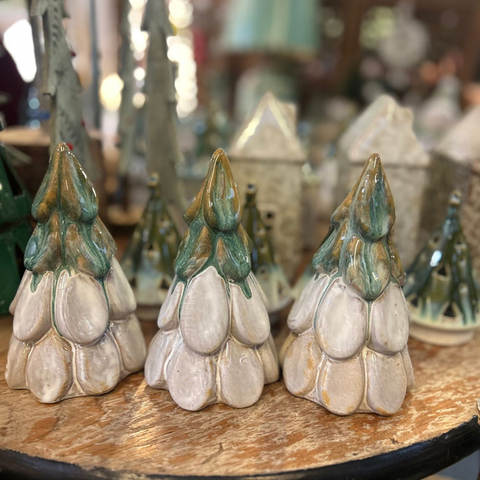Three ceramic tree-shaped objects on a wooden surface with blurred background