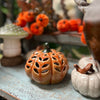 Decorative ceramic pumpkins and mushrooms on a rustic surface with blurred background