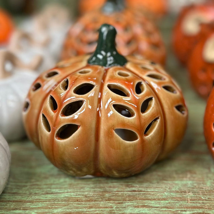 Ceramic pumpkin with decorative holes on a wooden surface