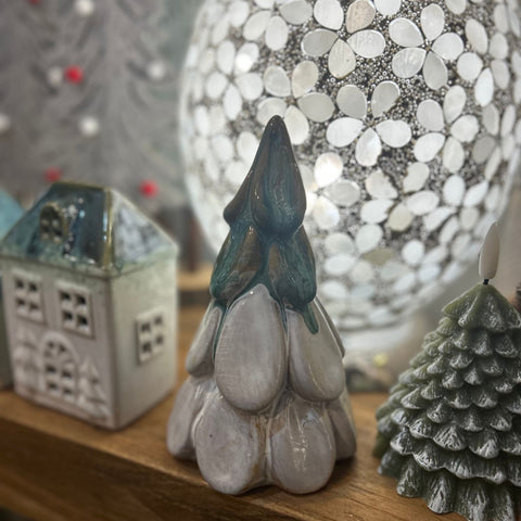 Decorative stone gnome figure with a house and tree in the background