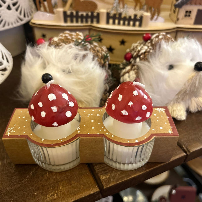 Decorative candles with red mushroom tops on a wooden stand.