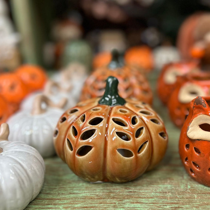 Decorative ceramic pumpkins with unique designs on a wooden surface.