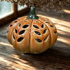 Ceramic pumpkin with decorative holes on a wooden surface