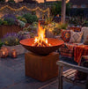 A large round metal fire pit bowl with a visible fire.