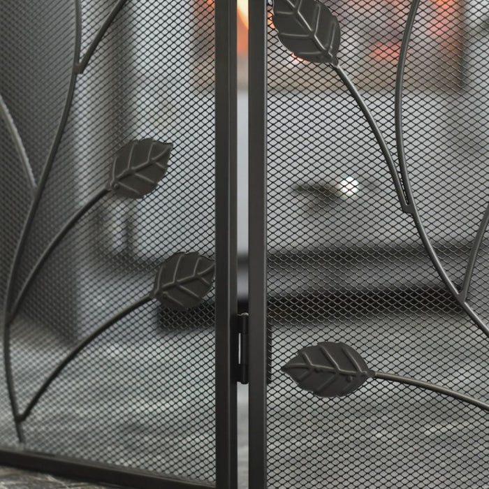 Black metal fireplace screen with leaf design in front of a fire.