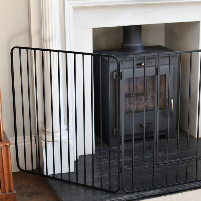 Black metal fireplace screen in front of a white fireplace.