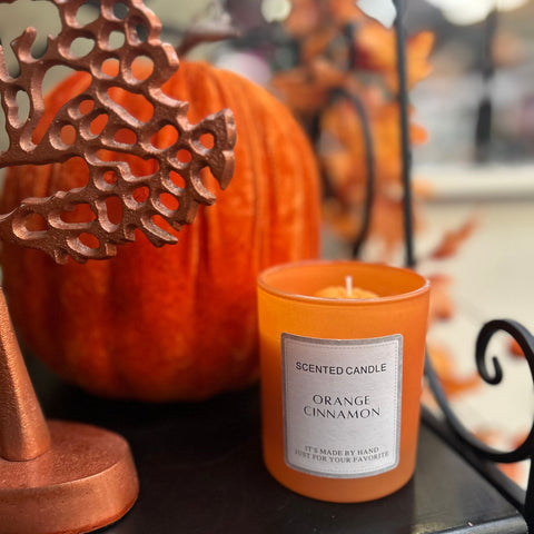 Orange cinnamon scented candle with decorative elements on a table