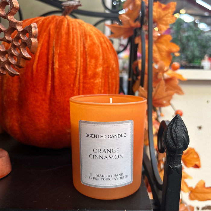 Orange cinnamon scented candle with a pumpkin and decorative elements in the background