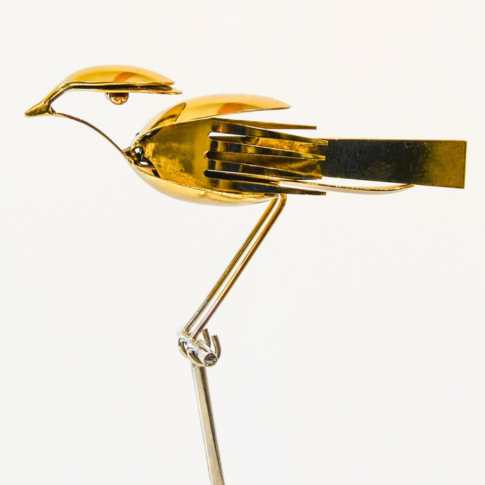 Gold bird-shaped brooch on a white background