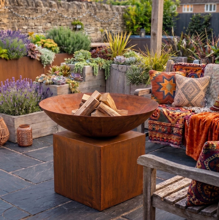 A large weathered metal fire pit bowl filled with logs,