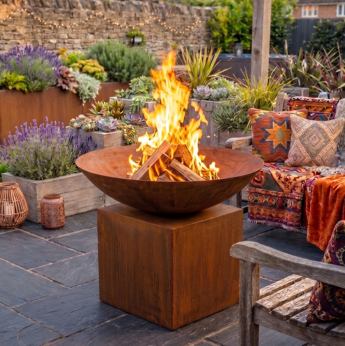 Rustic lit fire bowl on stand in garden 