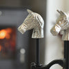 Decorative horse head sculptures in front of a fireplace