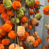 Decorative arrangement of orange, green, and brown pumpkins on branches