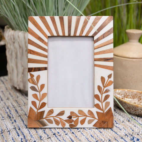 Decorative wooden picture frame with leaf patterns on a textured surface.