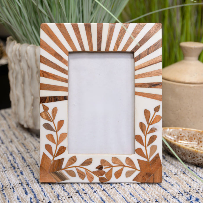 Decorative wooden picture frame with leaf patterns on a textured surface.