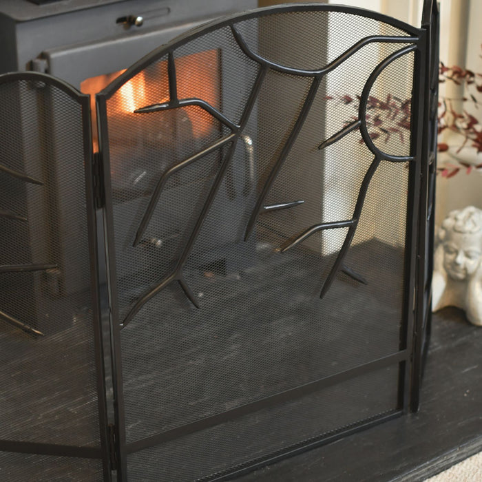Black metal fireplace screen with a fire burning inside