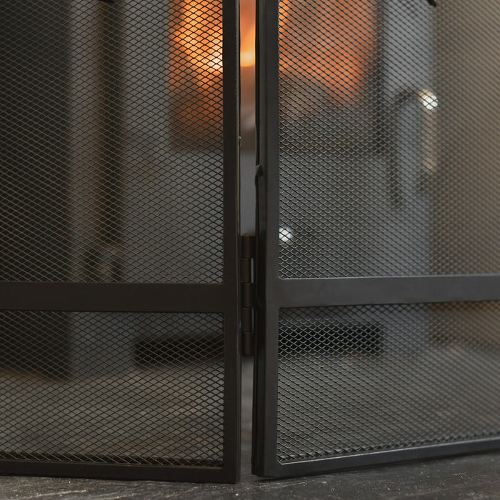Close-up of a black metal fireplace screen with a blurred background